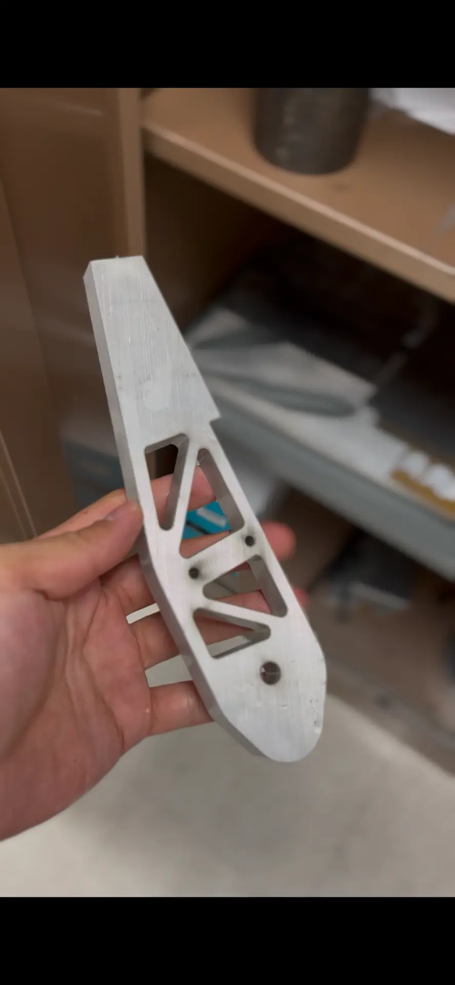 Machined pedal lever — aluminum arm after waterjet cutting and finishing, with triangular cutouts to pull mass out without losing stiffness.